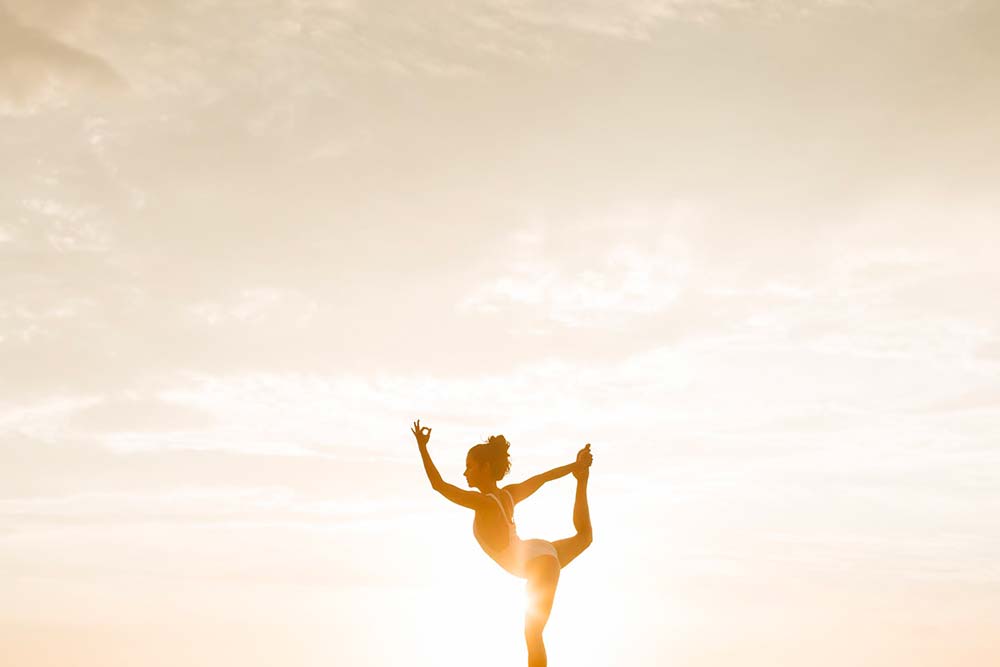 Silhouette d'une femme faisant du yoga au coucher du soleil.