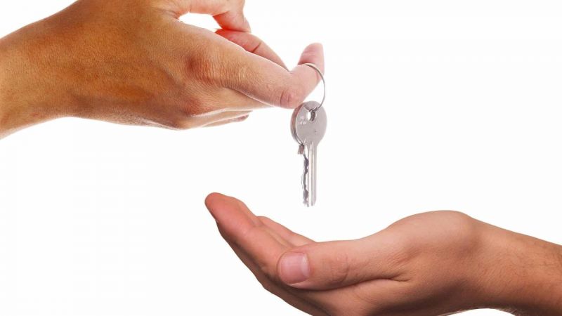 Une personne qui remet une clé à une autre personne.