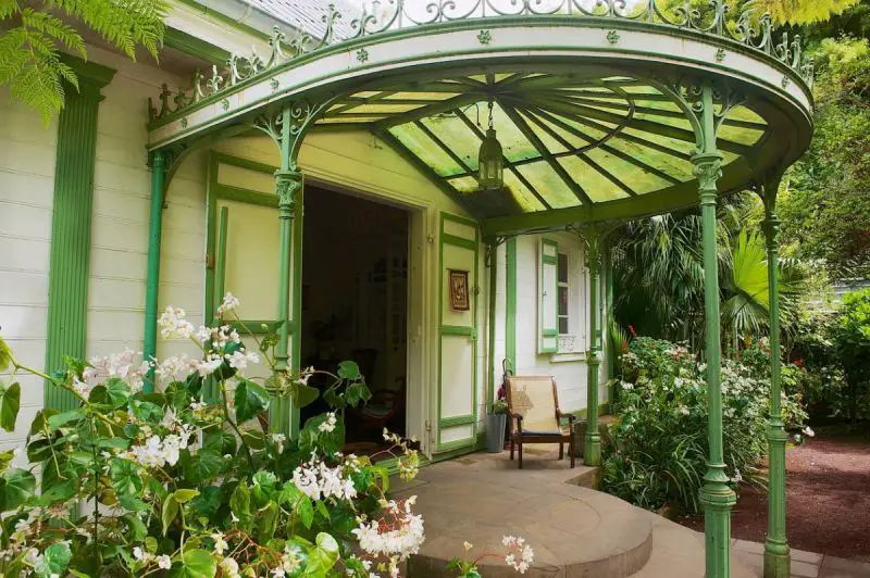 Une maison avec un porche vert et des fleurs.