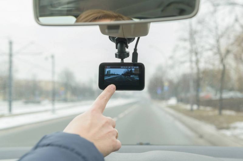 Une personne pointe une caméra sur le tableau de bord d'une voiture.