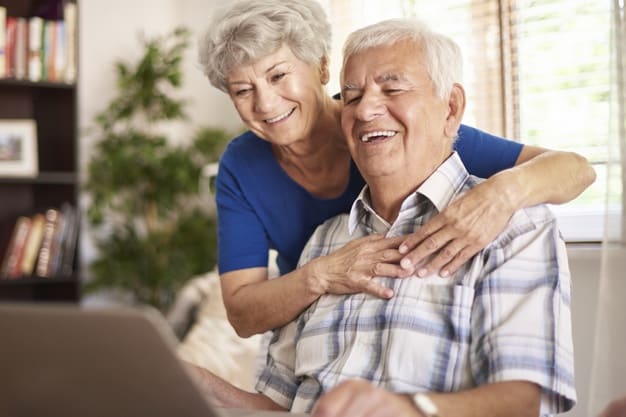 Un couple de personnes âgées utilise un ordinateur portable à la maison.