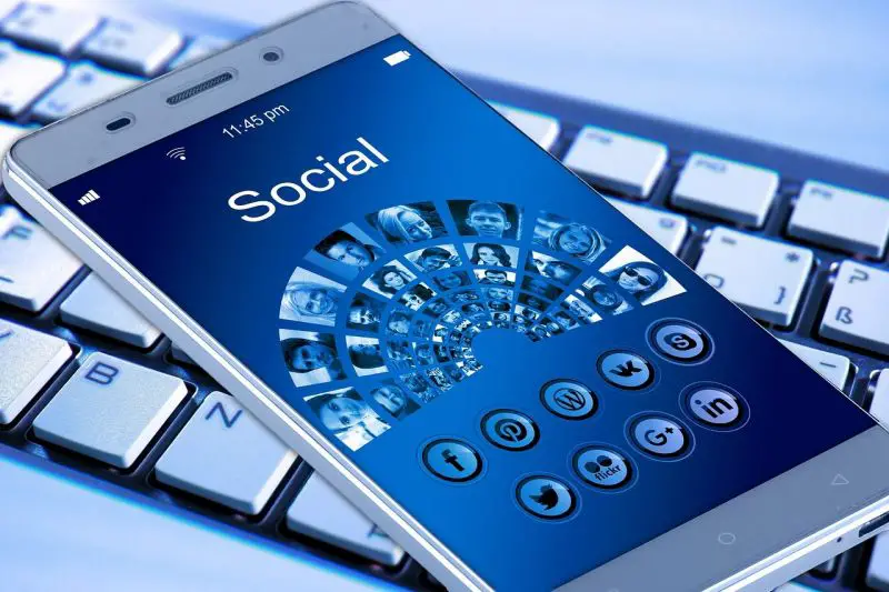 Un smartphone avec des icônes sociales dessus assis sur un clavier.