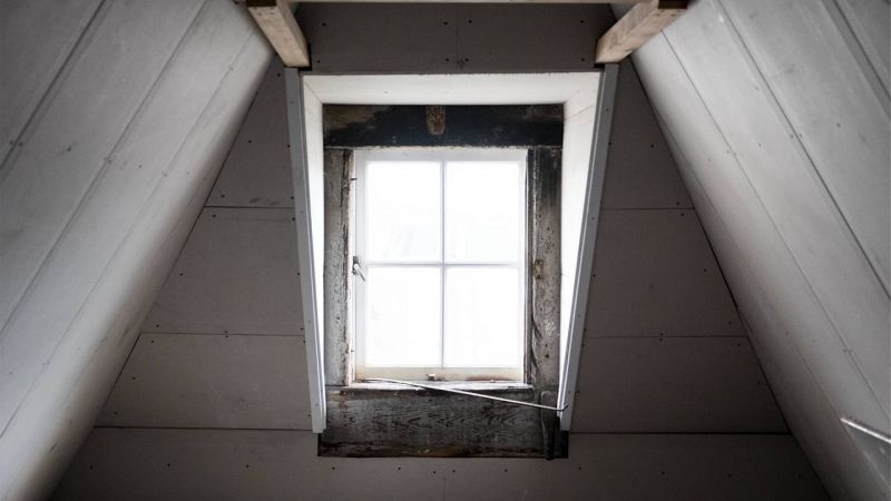 Une fenêtre dans un grenier avec un cadre en bois.