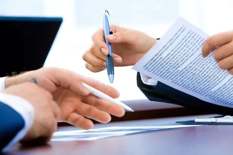Deux hommes d'affaires signant un document à une table.