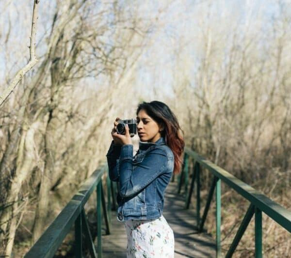 Une femme prenant une photo avec son appareil photo sur un pont dans les bois