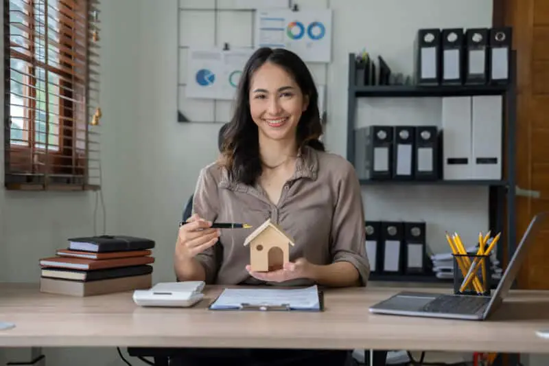 Femme asiatique tenant un modèle de maison à son bureau