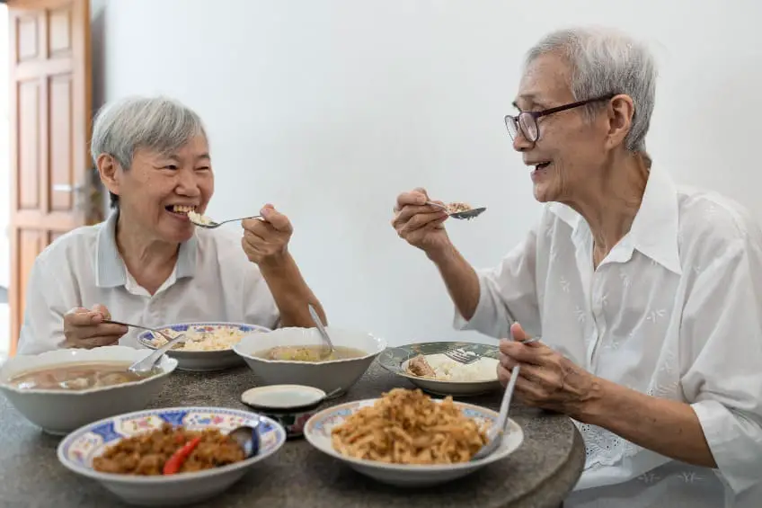 Deux personnes âgées mangeant ensemble à une table.