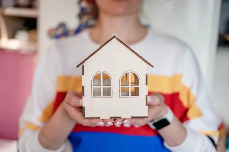 Une femme brandissant une maquette en bois d’une maison