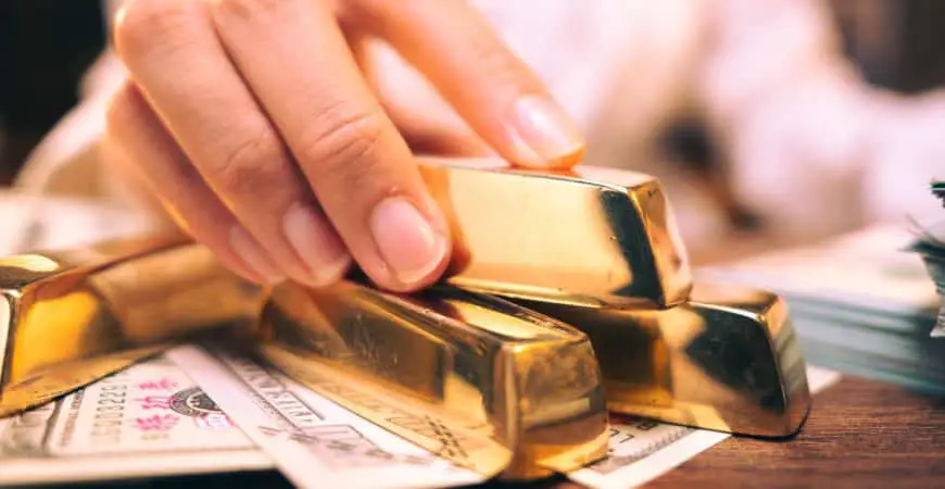 Une femme tient des lingots d’or et de l’argent sur une table