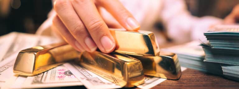 Une femme tient des lingots d’or et de l’argent sur une table