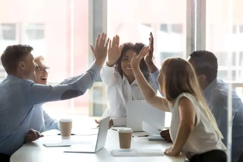 Un groupe de gens d'affaires levant la main lors d'une réunion.