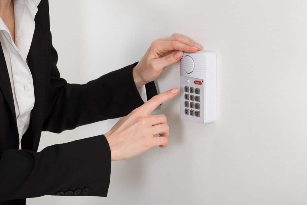 Une femme en costume appuyant sur un bouton d’un système d’alarme.