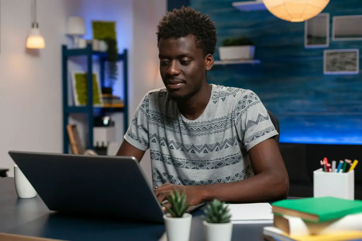 Un jeune homme assis à un bureau avec un ordinateur portable