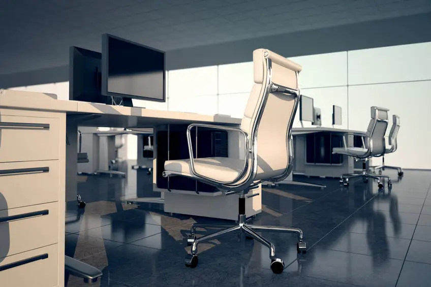Un bureau avec des bureaux, des chaises et des moniteurs blancs.