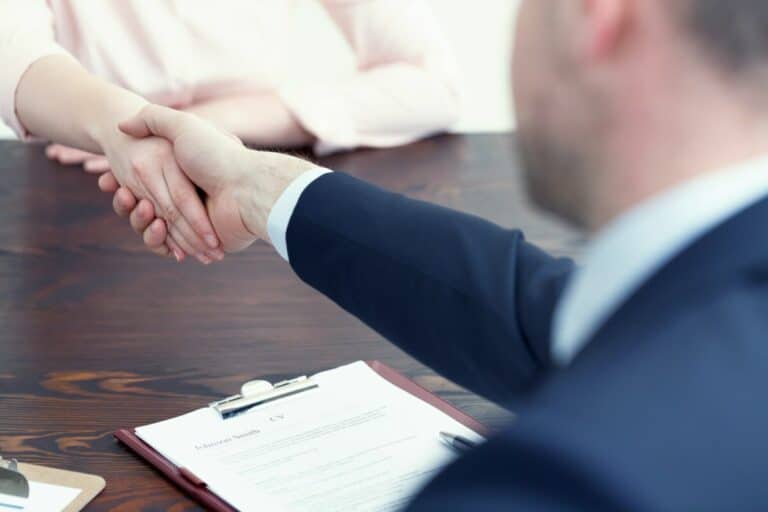 Entretien entre un homme et une femme se serrant la main à un bureau