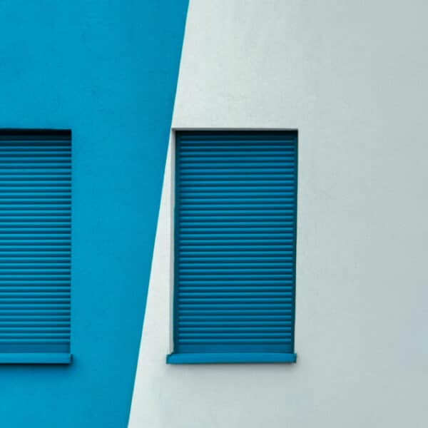 Deux volets bleus et blancs sur un mur.