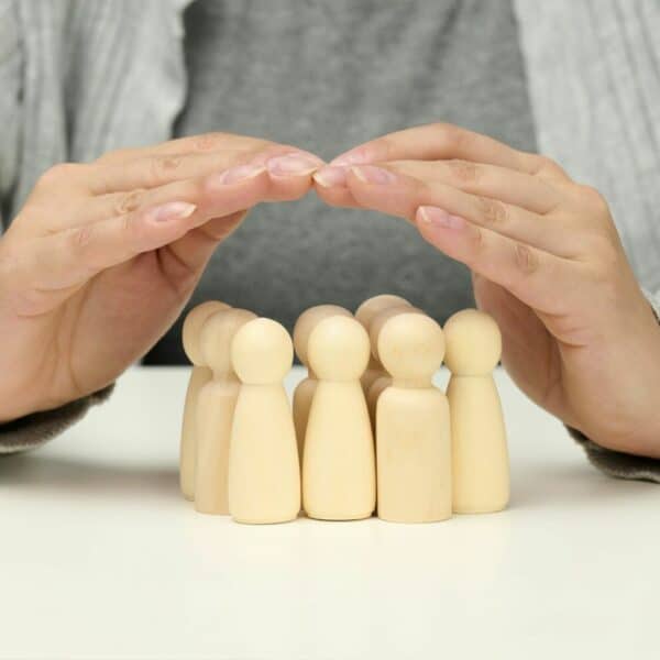 Wooden figurines of men, a family guarded by two female hands. Help, life insurance