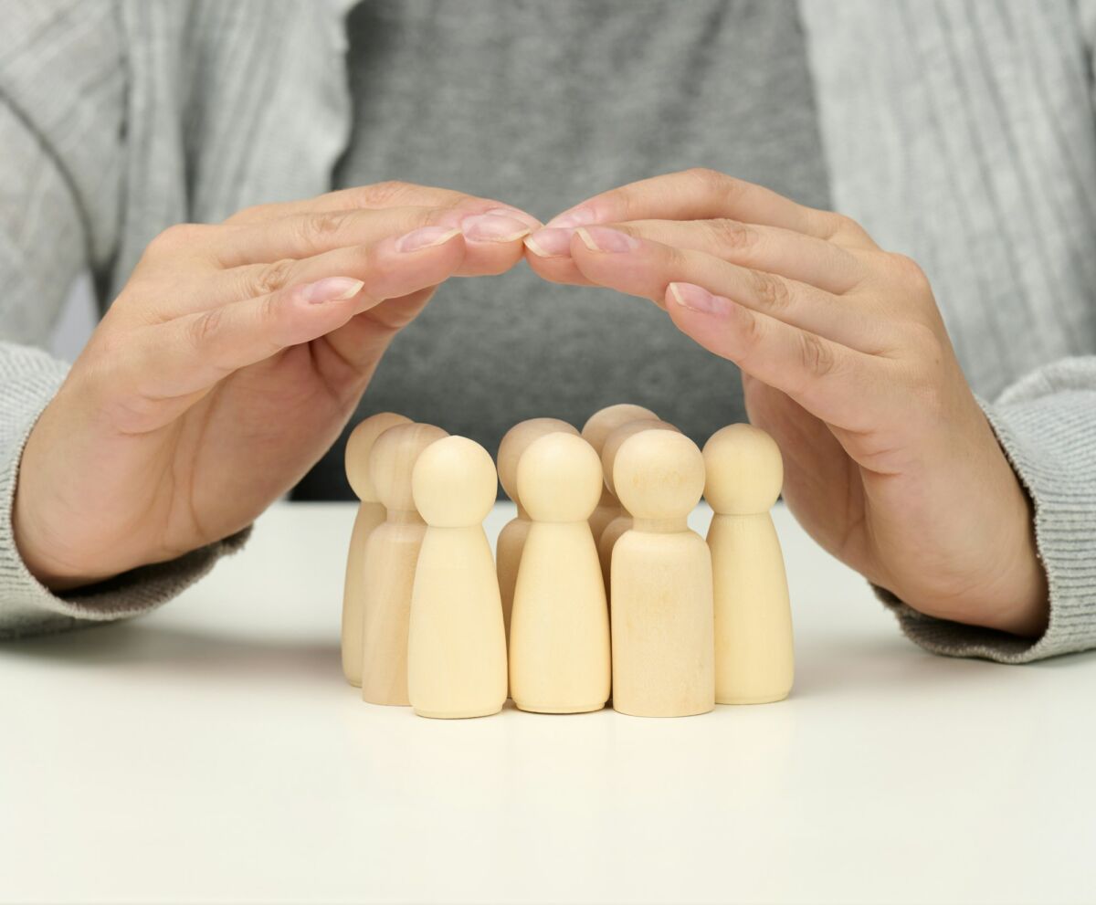 Wooden figurines of men, a family guarded by two female hands. Help, life insurance