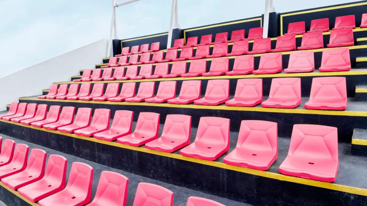 Sièges de stade rouges vides disposés en rangées avec des bandes jaunes entre les deux.