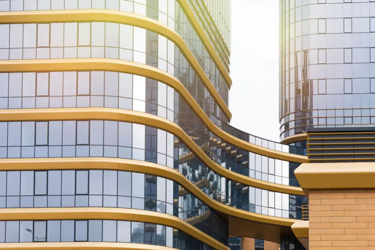 Immeuble de bureaux en verre avec des accents jaunes incurvés reflétant le ciel